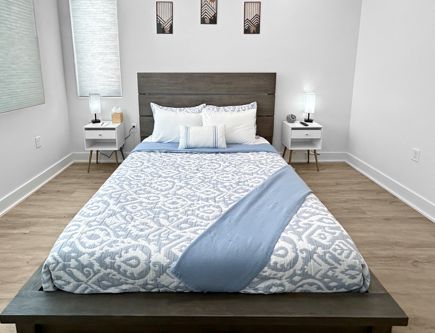 Sink into this plush bed with crisp linens and soft blue accents. Stylish nightstands and warm lighting create your perfect retreat.