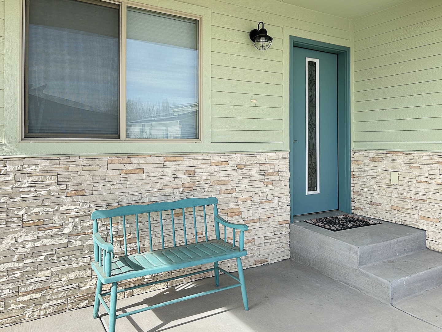 Step into your charming retreat through this welcoming entrance, where a cozy turquoise bench invites you to pause and soak in the peaceful atmosphere.