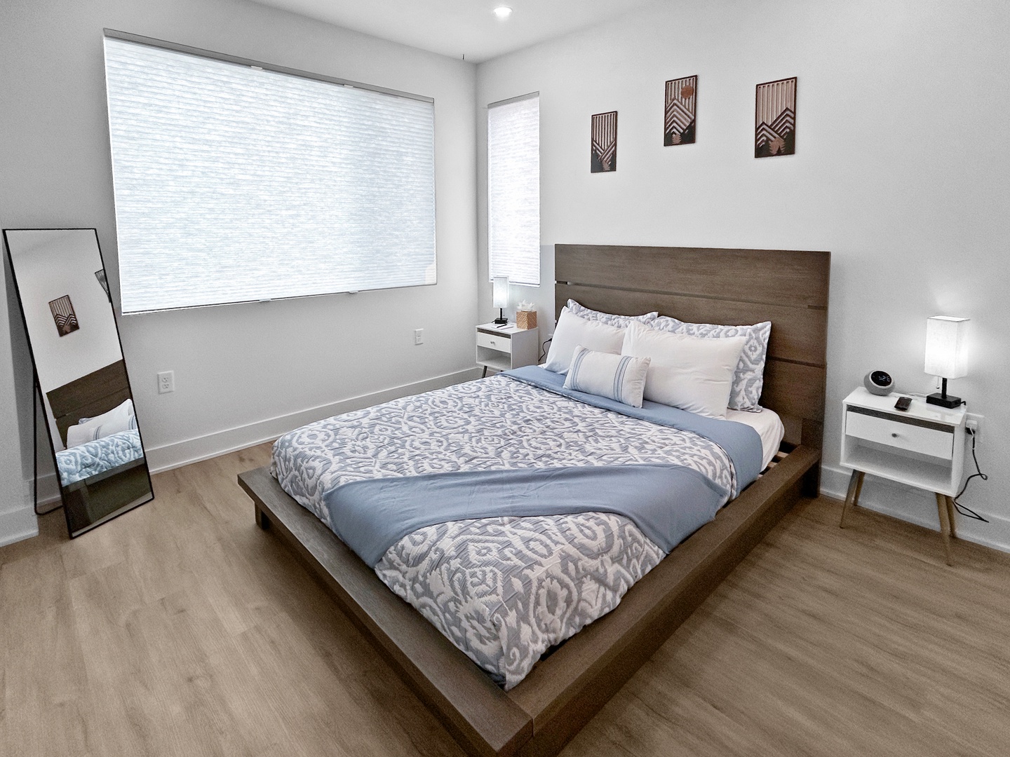 Unwind in your serene bedroom with soft blue linens, modern furnishings, and natural light filtering through privacy blinds for peaceful rest.