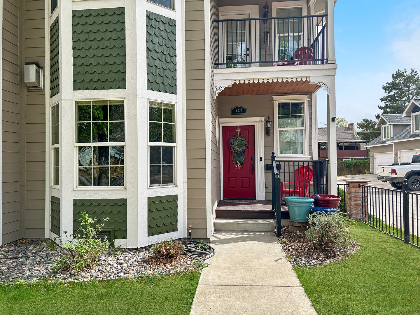 Charming property entrance with welcoming red door and covered porch area in a peaceful residential neighborhood.