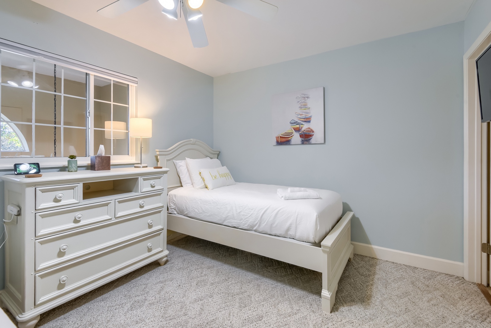 Fresh white bedding and a ceiling fan keep this twin room comfortable