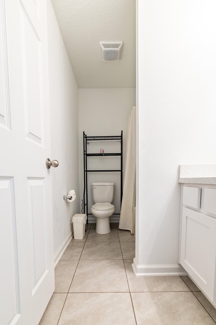 A clean, compact bathroom with everything you need, including a handy shelf above the toilet for your toiletries and extra storage below for towels.