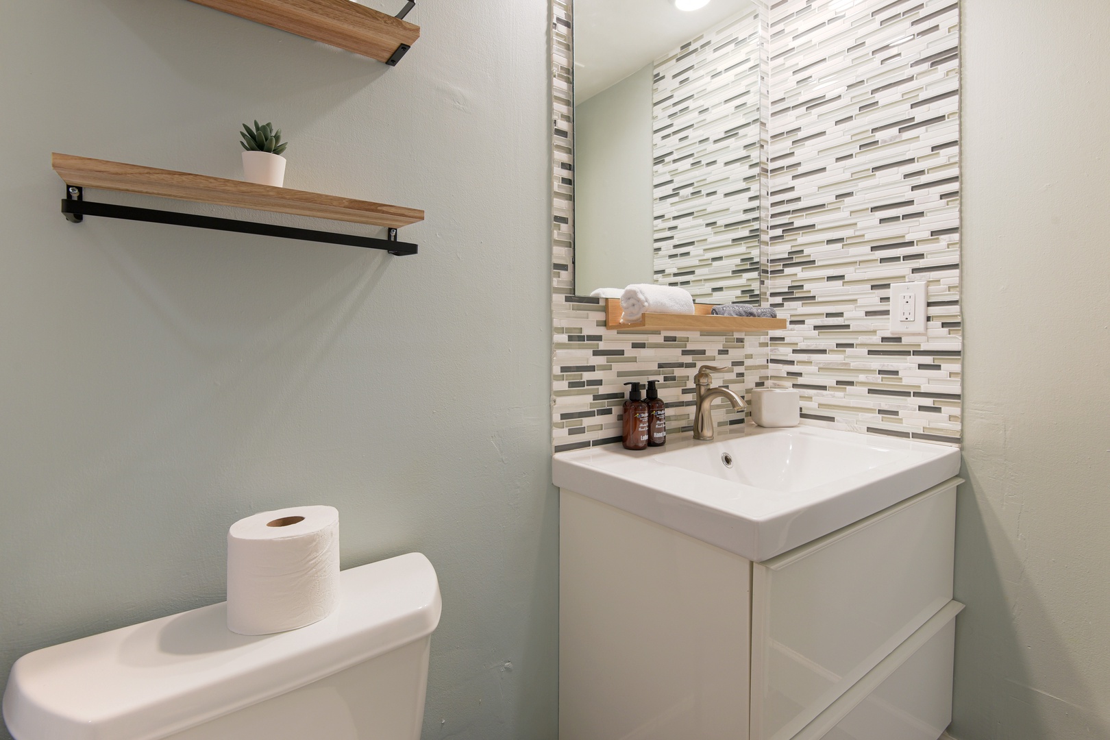 Updated bathroom with mosaic tile, floating vanity and open shelving