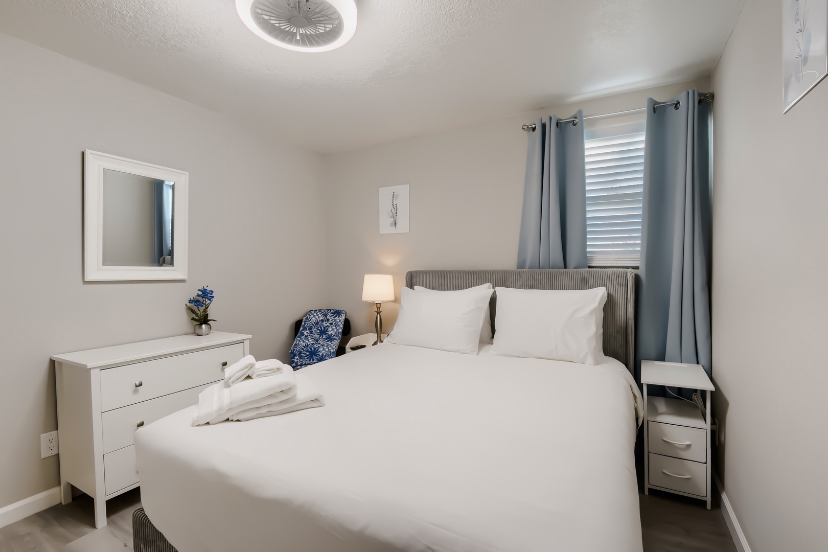 Primary queen bedroom with dresser, reading lamp, and blackout curtains