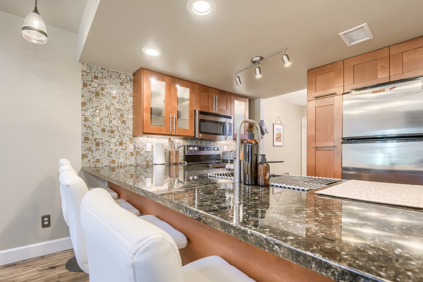 Granite breakfast bar, mosaic tile backsplash and stainless refrigerator