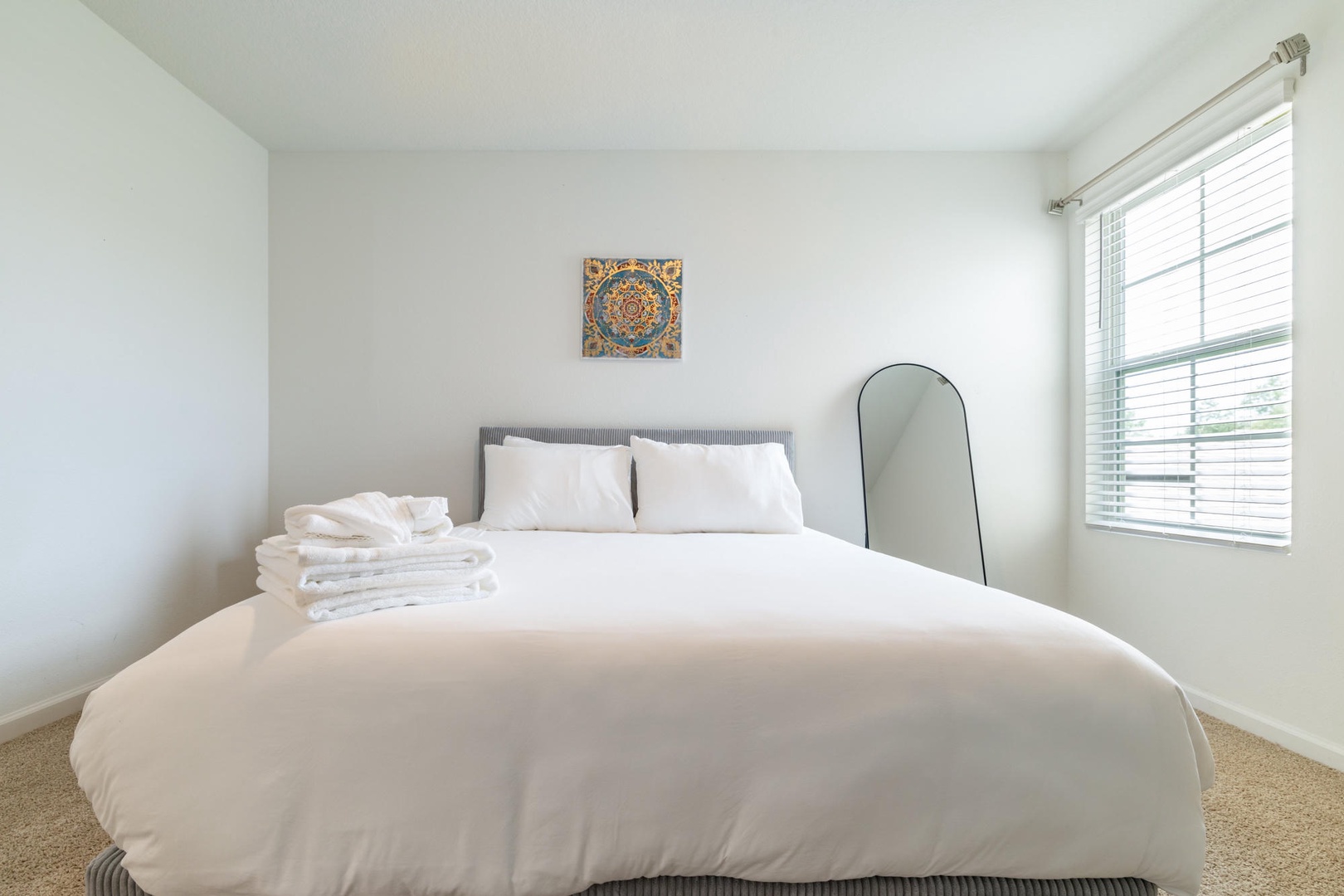 Drift off to sleep surrounded by soft white linens and peaceful simplicity. Your restful escape awaits in this serene bedroom with plush towels at your fingertips.