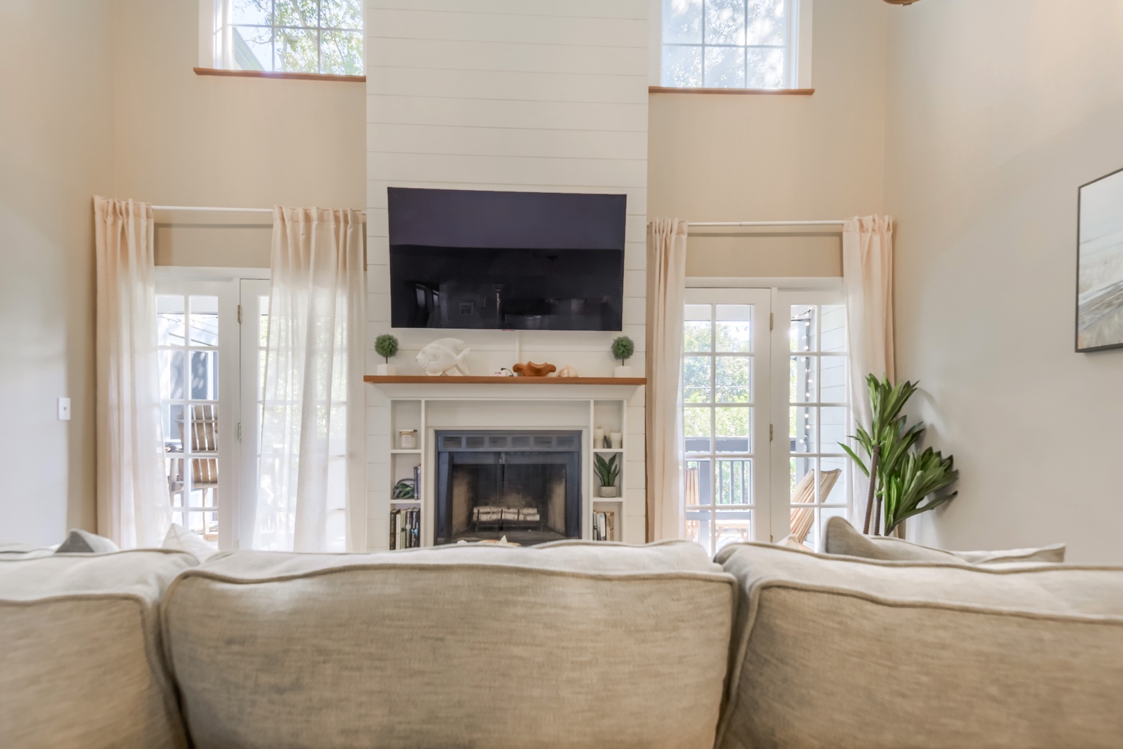 Two stories of windows and French doors frame the fireplace and TV