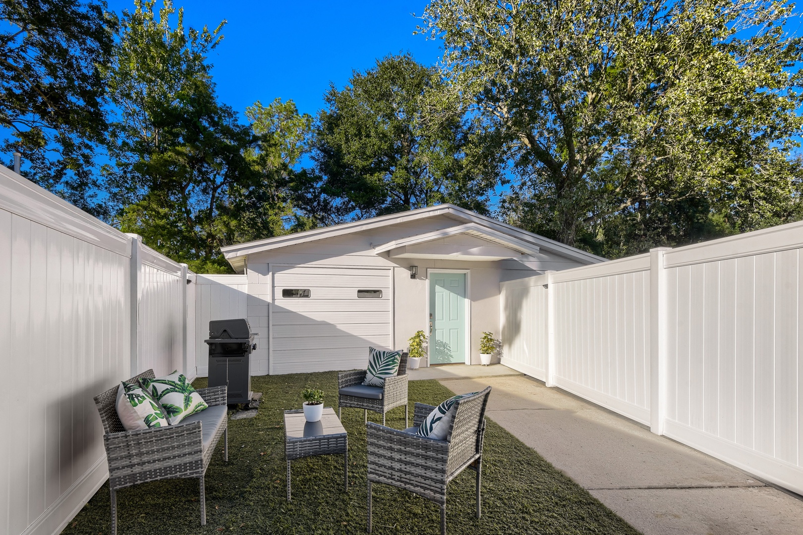 Private fenced backyard patio with seating, gas grill, and guest suite entrance