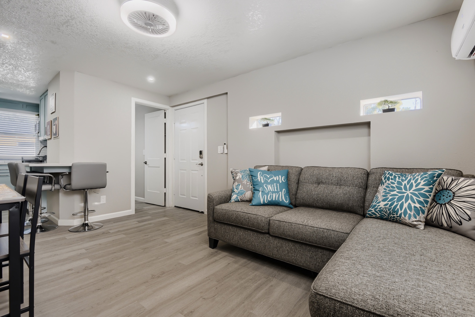 Open living area flowing to the kitchen breakfast bar and entry
