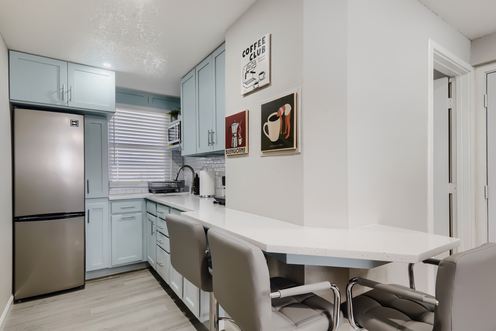Kitchen with full-size fridge, quartz breakfast bar, and bar stools