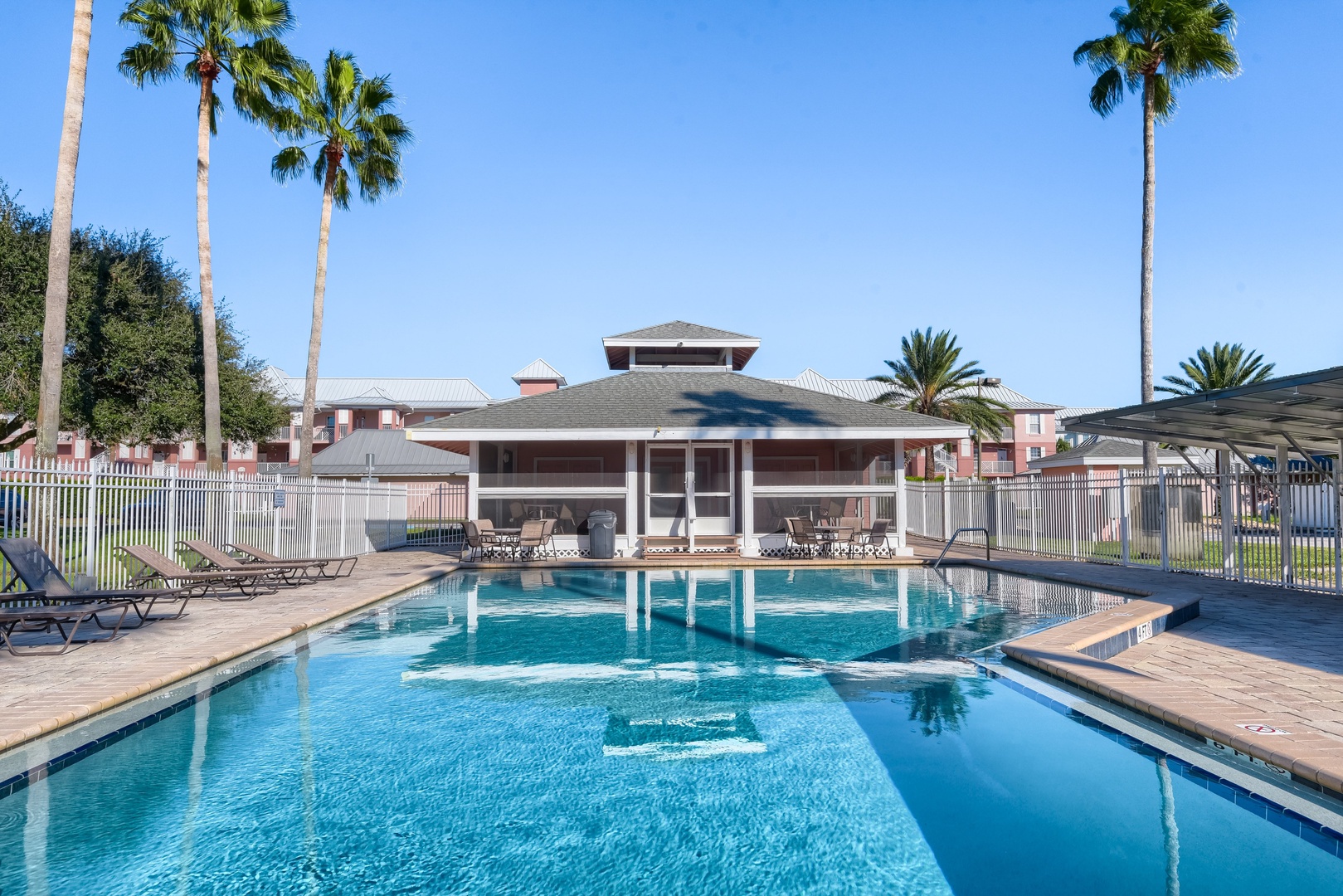 Sparkling pool with lounge chairs, palm trees and a shaded pavilion