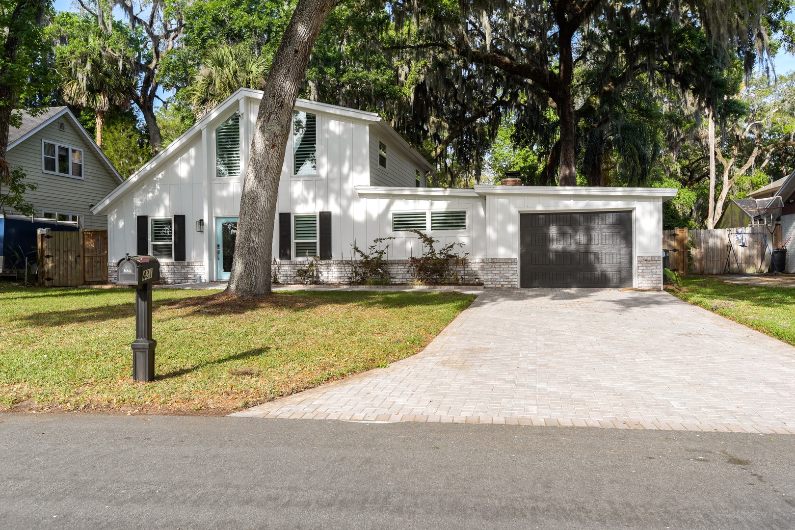 Modern home nestled under mature oak trees.
