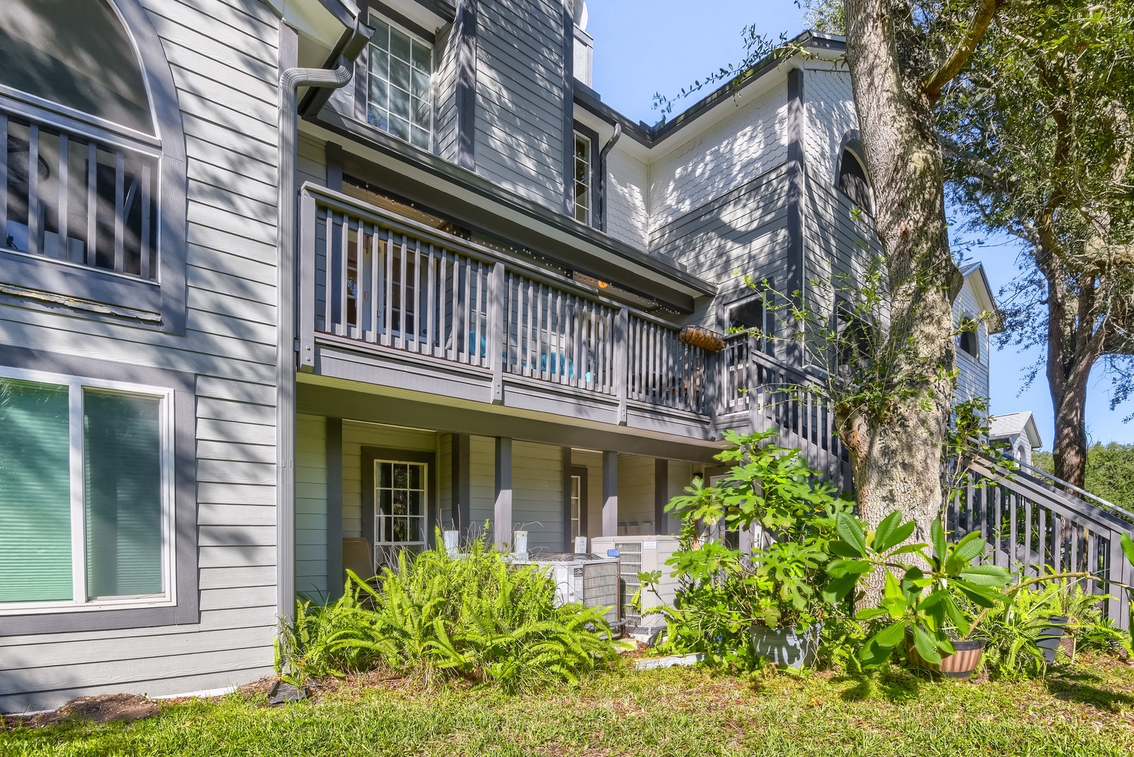 Back of the townhome with deck above and lush tropical landscaping