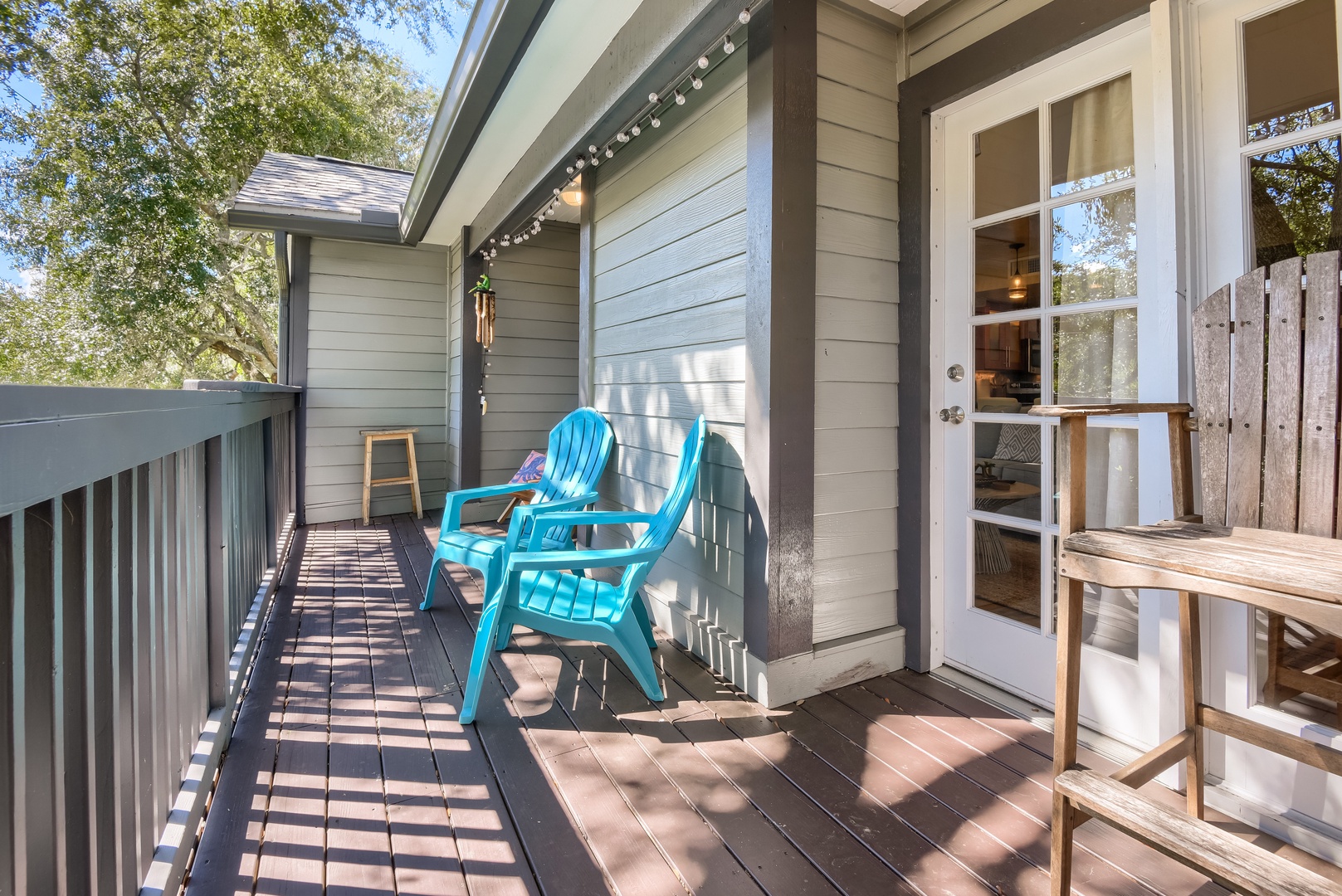 Long deck with string lights, colorful chairs and leafy views