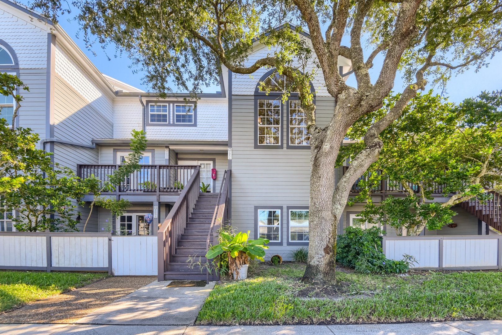 Front of the townhome with a grand live oak and fenced patio