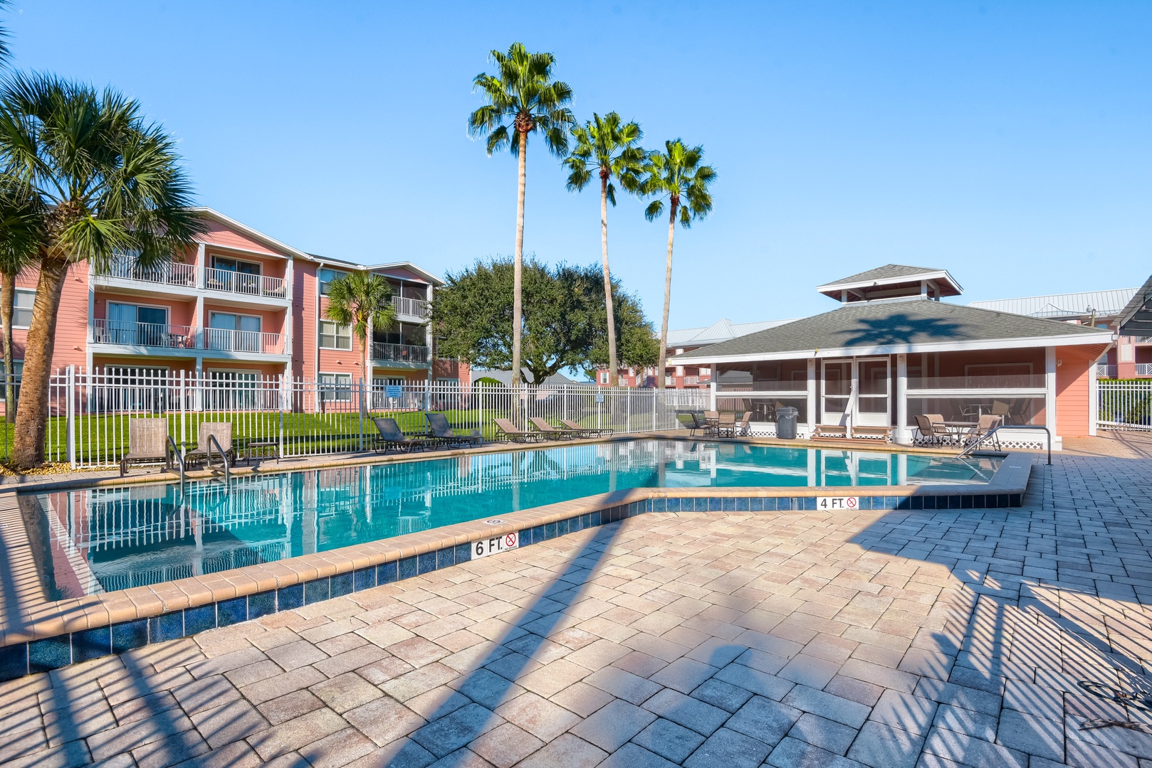 Pool deck with plenty of loungers, palms and sunny Florida skies