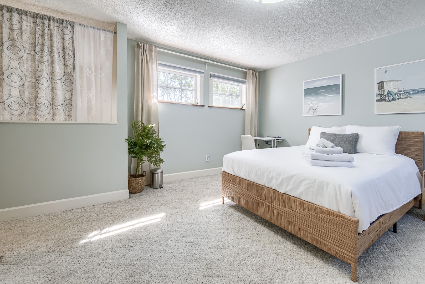 Sunlit primary bedroom with woven bed frame and soft carpet