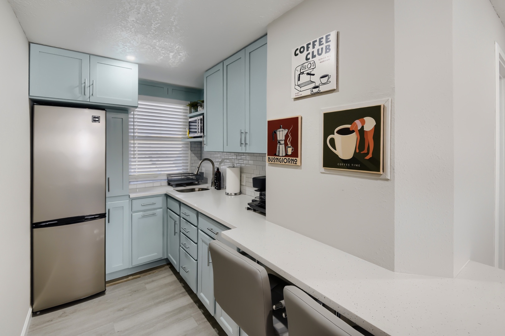 Kitchen with light blue cabinets, fridge, and quartz counters