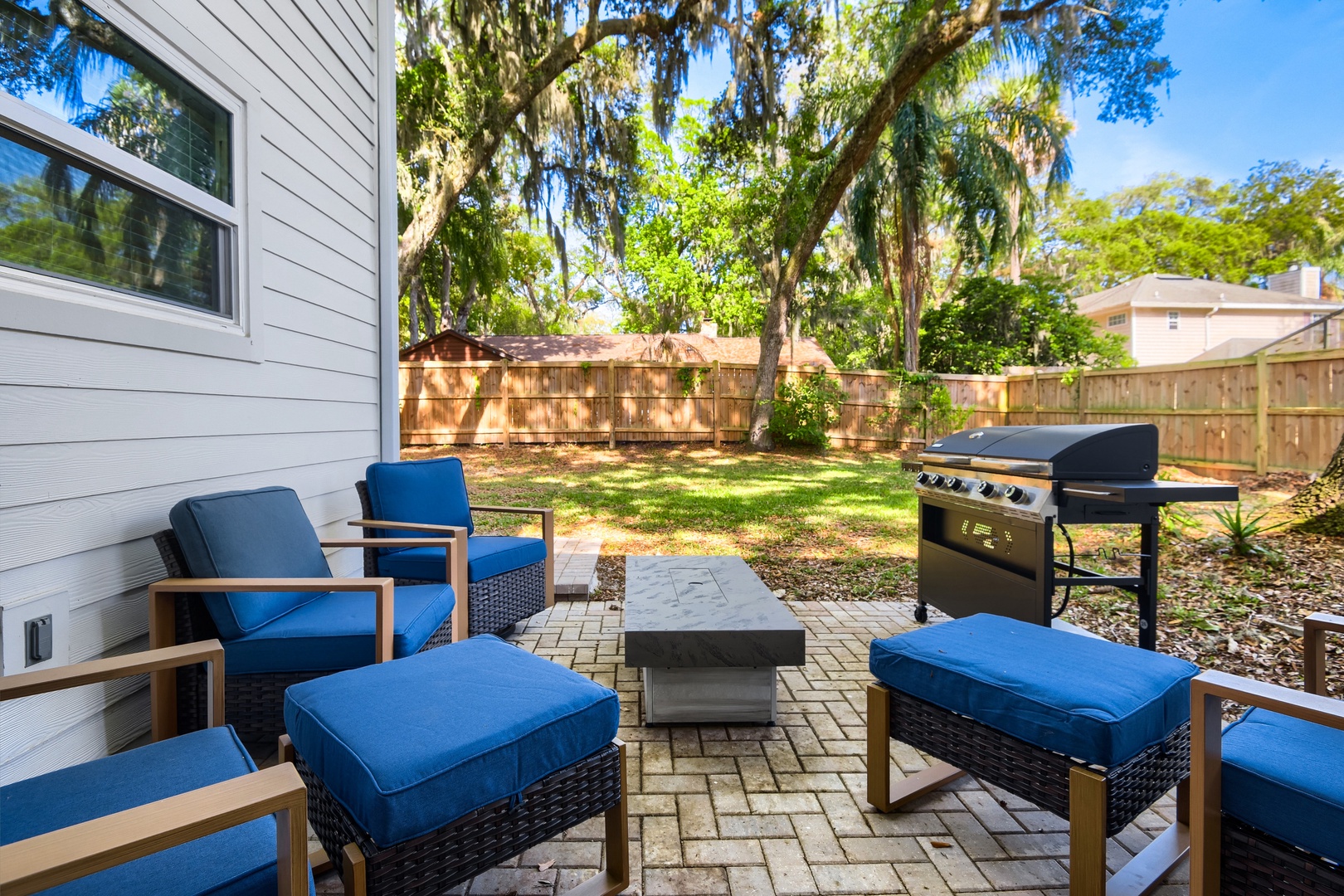 Comfortable seating and BBQ grill, with tropical landscaping.