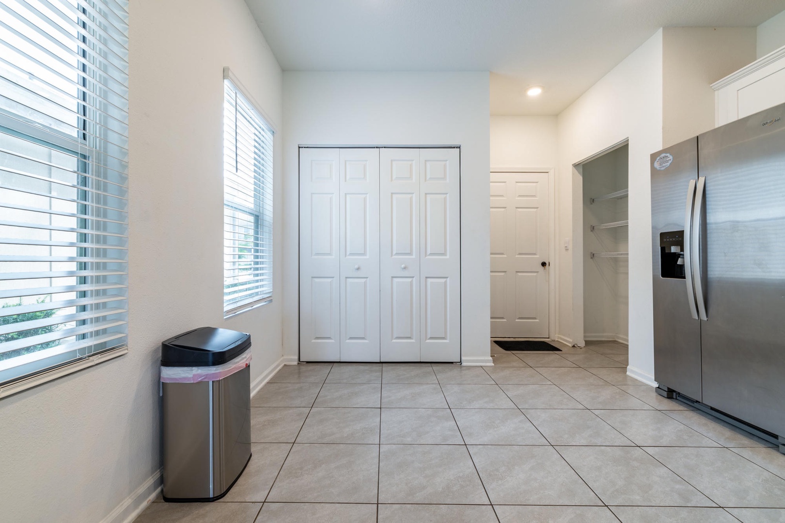 Your open entryway flows into the kitchen with clean tile floors and modern appliances, including a spacious fridge ready for all your groceries.