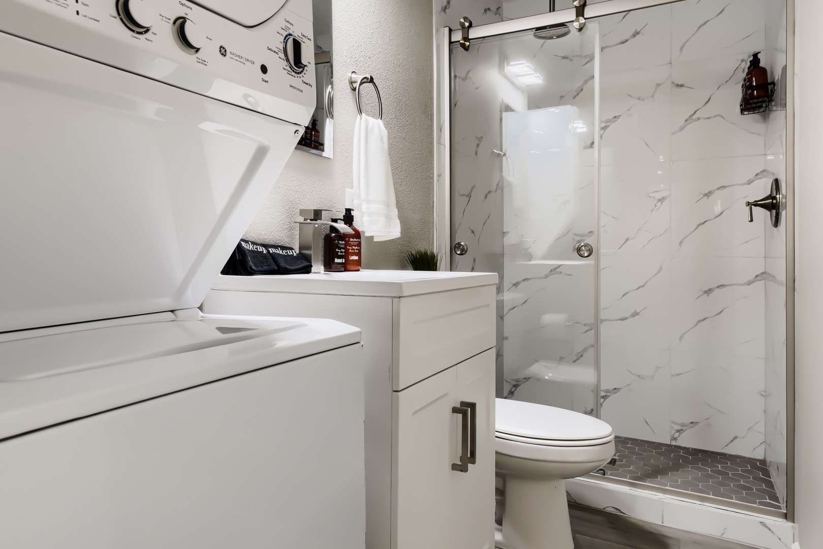 Bathroom with walk-in glass shower and stacked washer and dryer