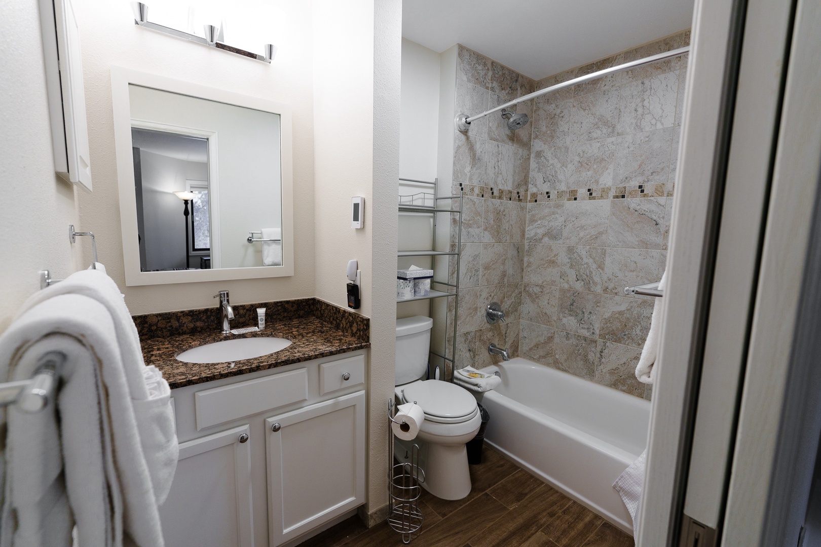 Private primary ensuite bathroom features marble-style tile work, granite countertops, and a relaxing tub-shower combination for your comfort and convenience.
