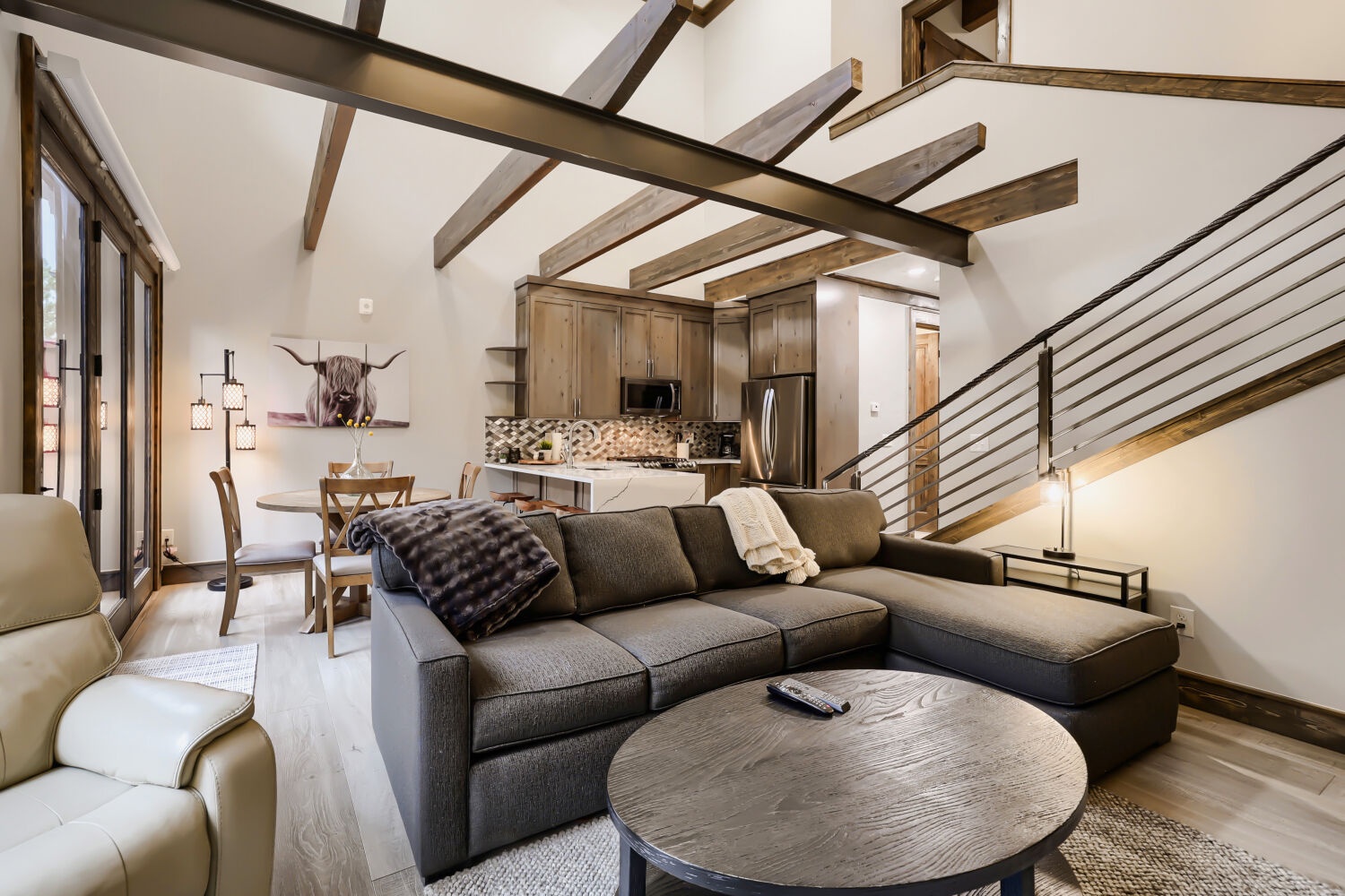 Relax in your open-concept living space with vaulted ceilings, exposed wood beams, and modern rustic charm that invites you to unwind after a day of adventure.