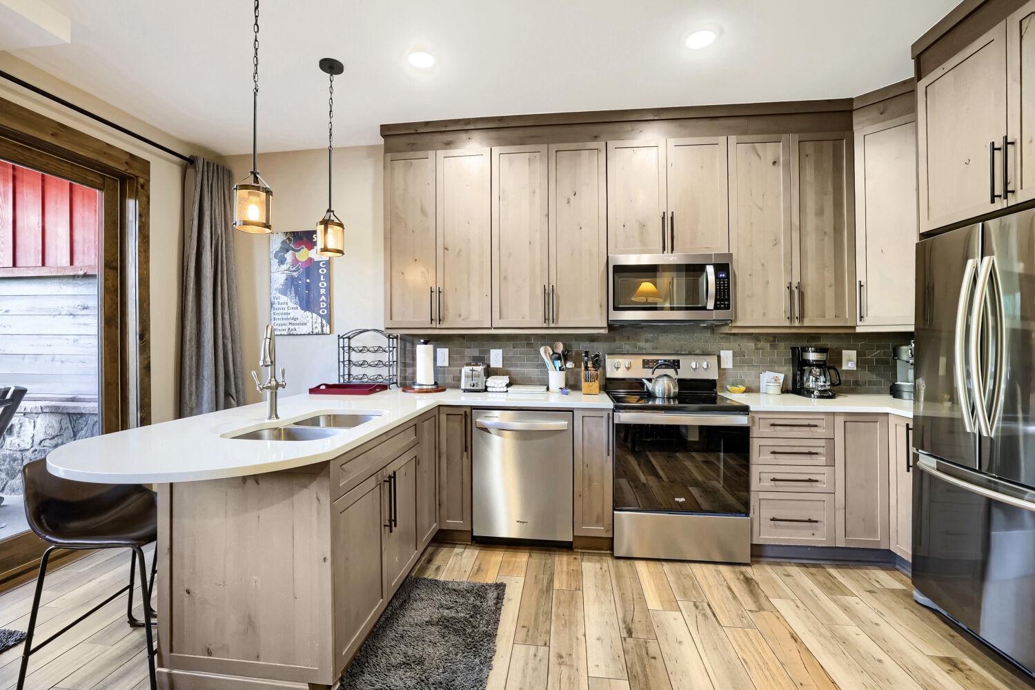 Your fully equipped kitchen features warm wood cabinetry, modern stainless steel appliances, and a spacious island perfect for preparing meals or gathering with loved ones during your mountain retreat.