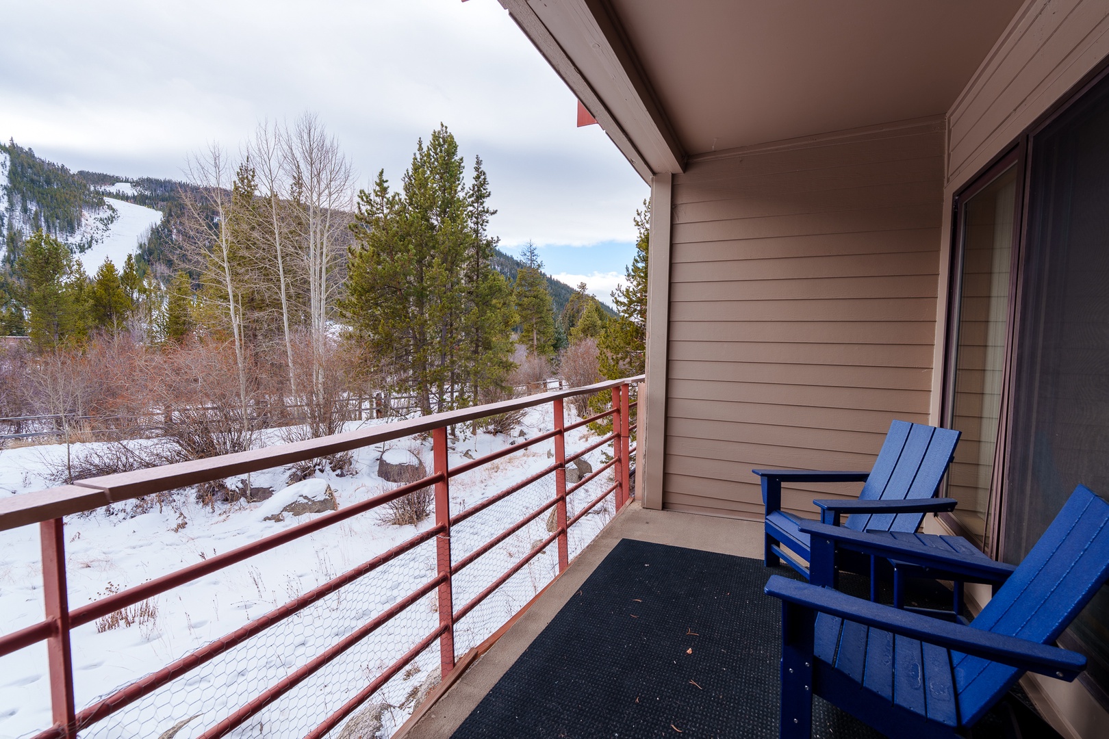 Step onto your private balcony and breathe in crisp mountain air while enjoying stunning winter views from your cozy blue chairs.