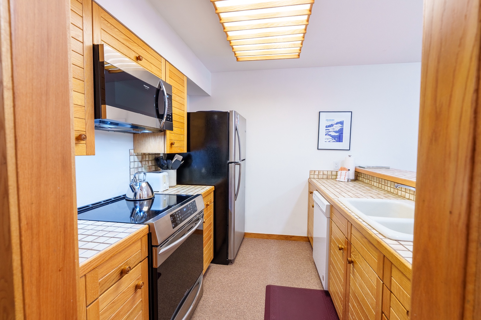 Your fully equipped kitchen awaits with warm wood cabinets, modern appliances, and a bright skylight overhead for memorable meal prep.