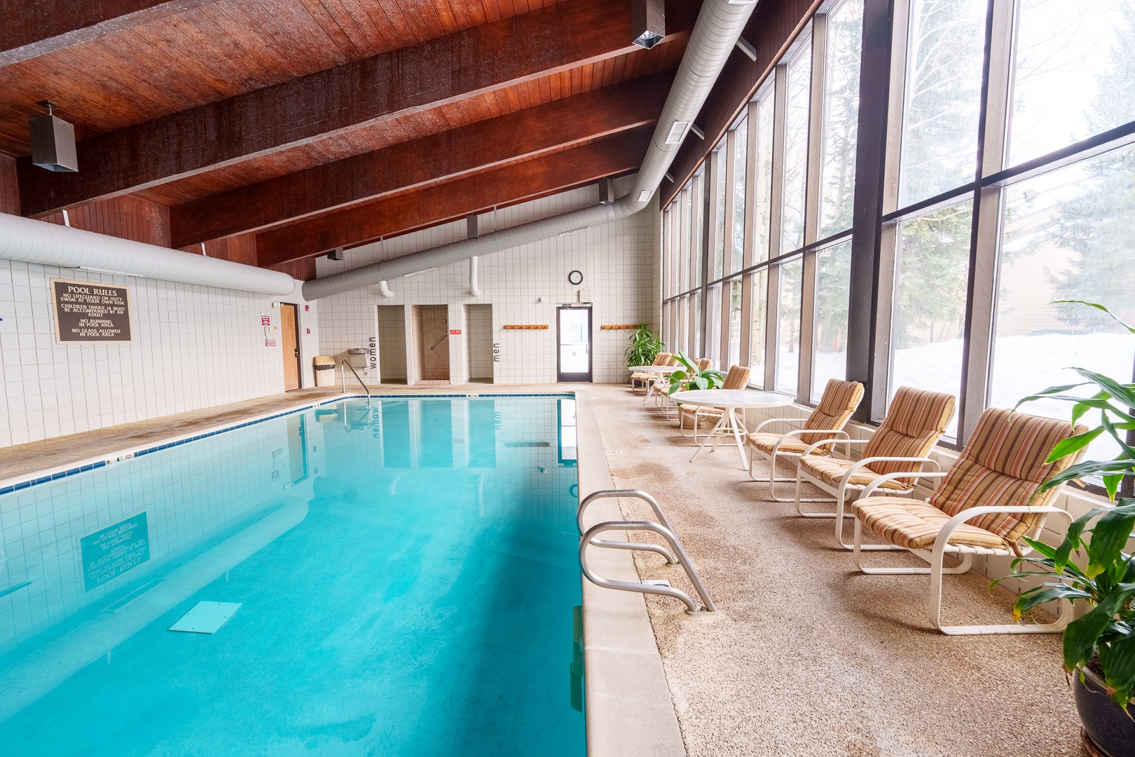 Dive into crystal-clear waters in this stunning indoor pool, where warm wooden beams and floor-to-ceiling windows create your perfect retreat.