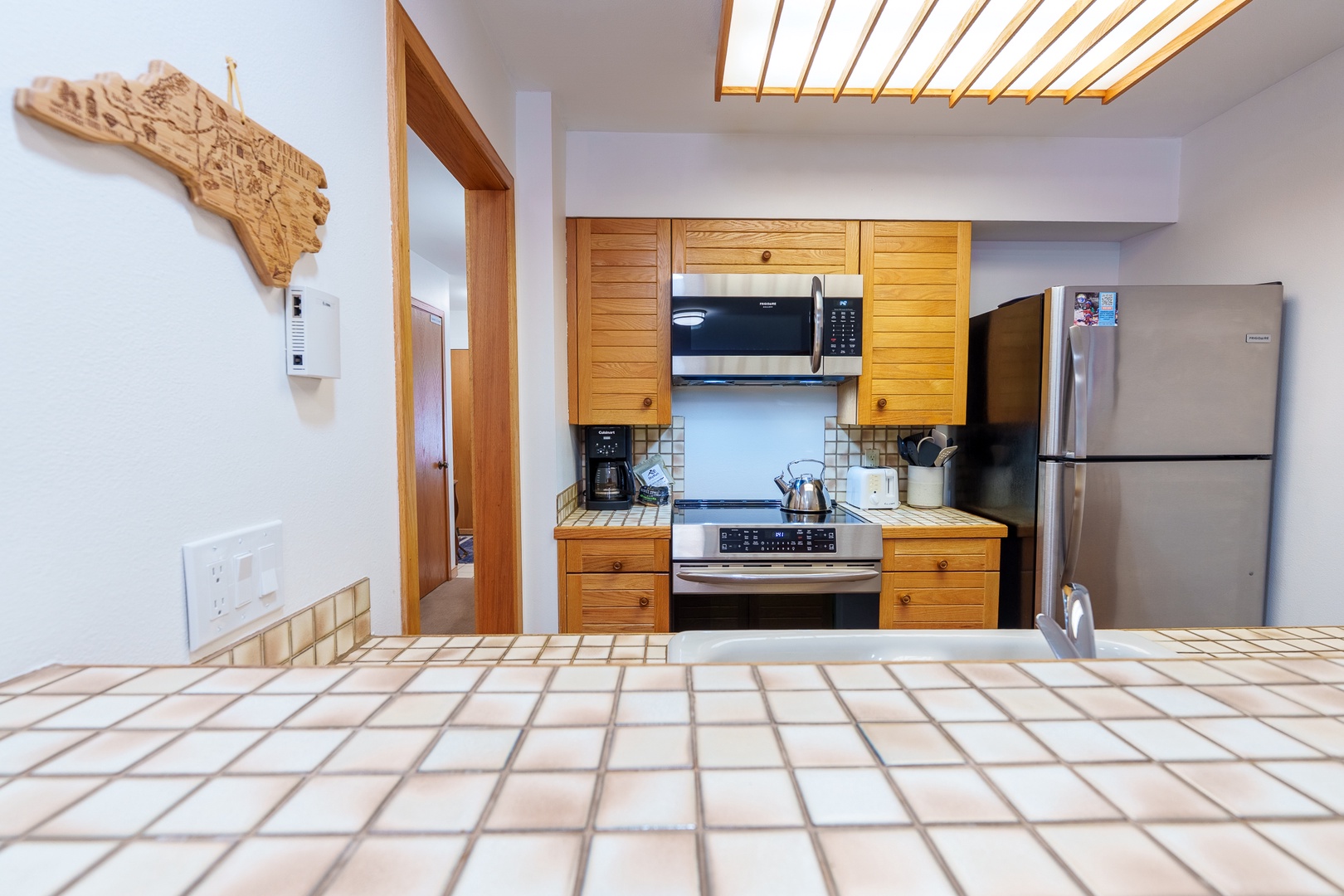 Your fully equipped kitchen features warm wood cabinetry, modern appliances, and charming tile countertops perfect for preparing meals during your stay.