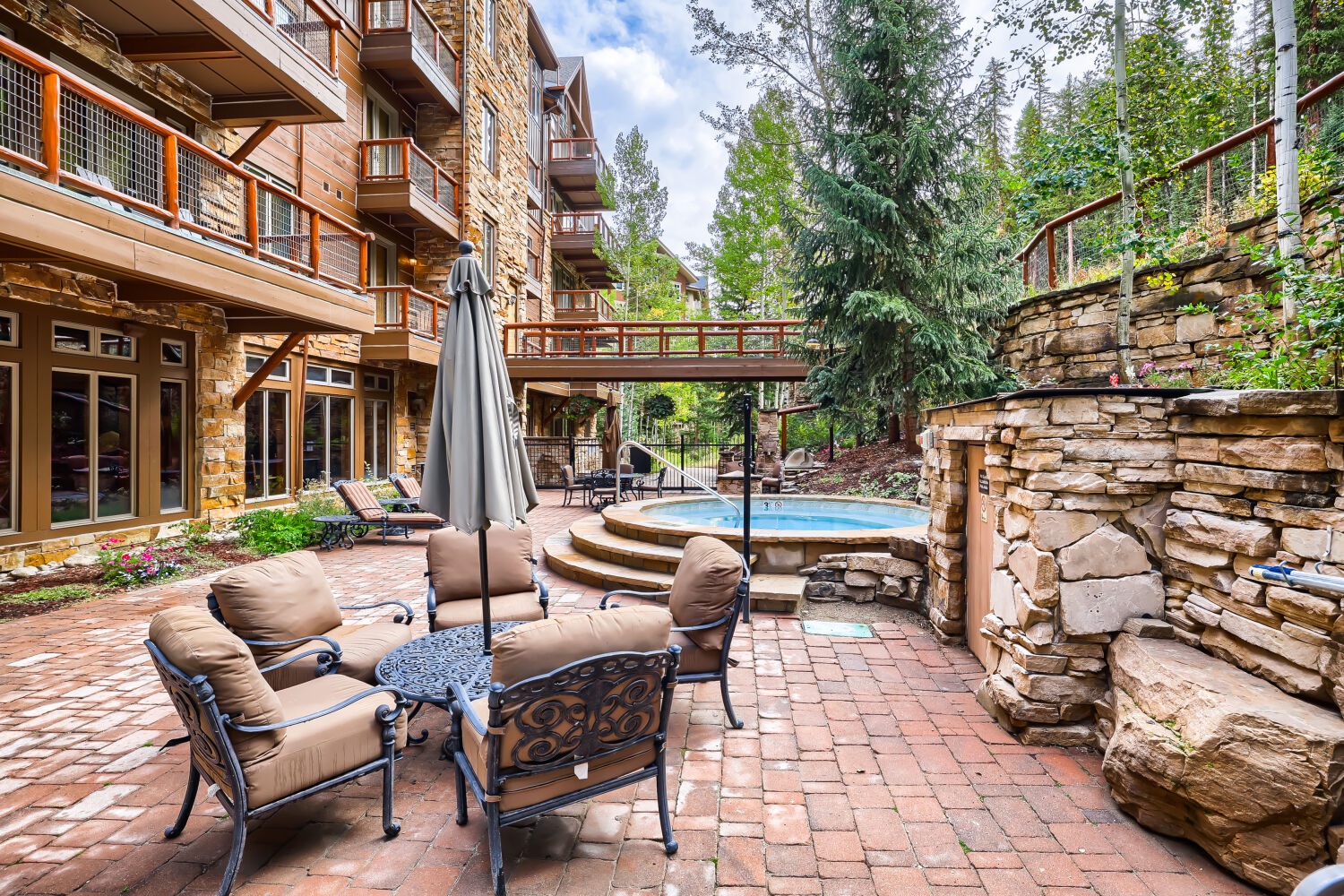 A resort-style setting awaits with natural stone accents, cozy seating, and a hot tub nestled among towering pines. Picture mornings here with coffee in hand, surrounded by mountain tranquility.