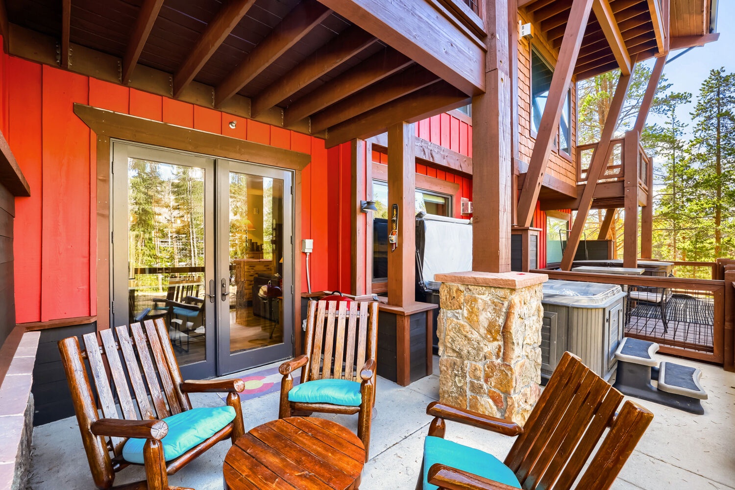 Unwind on your private deck with rustic rocking chairs, a stone-accented hot tub, and peaceful views of the surrounding pines—your perfect mountain escape awaits.