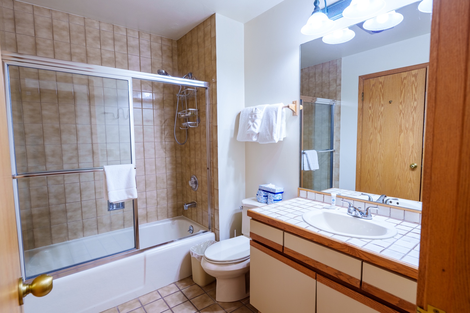 Step into your private bathroom featuring a spacious shower-tub combo with sliding glass doors and fresh towels awaiting your arrival.