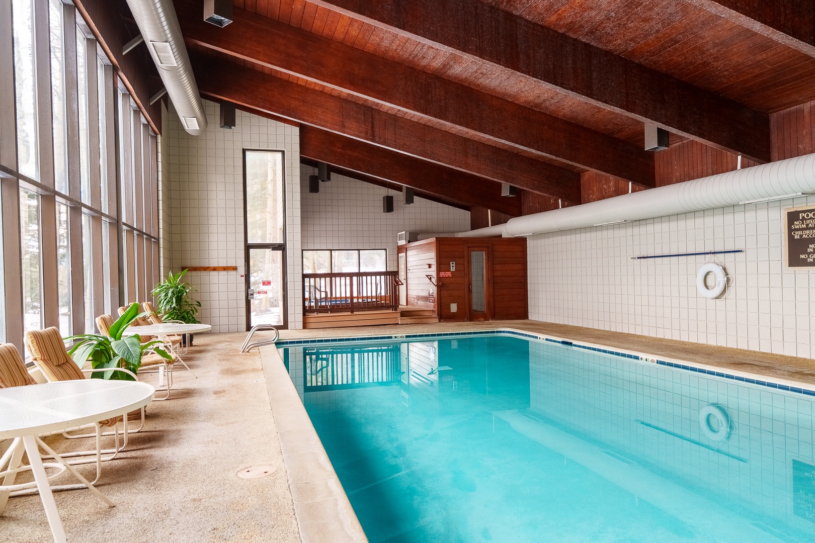 Dive into your private indoor oasis, where exposed wooden beams frame crystal-clear waters and poolside loungers invite endless relaxation beneath soaring ceilings.