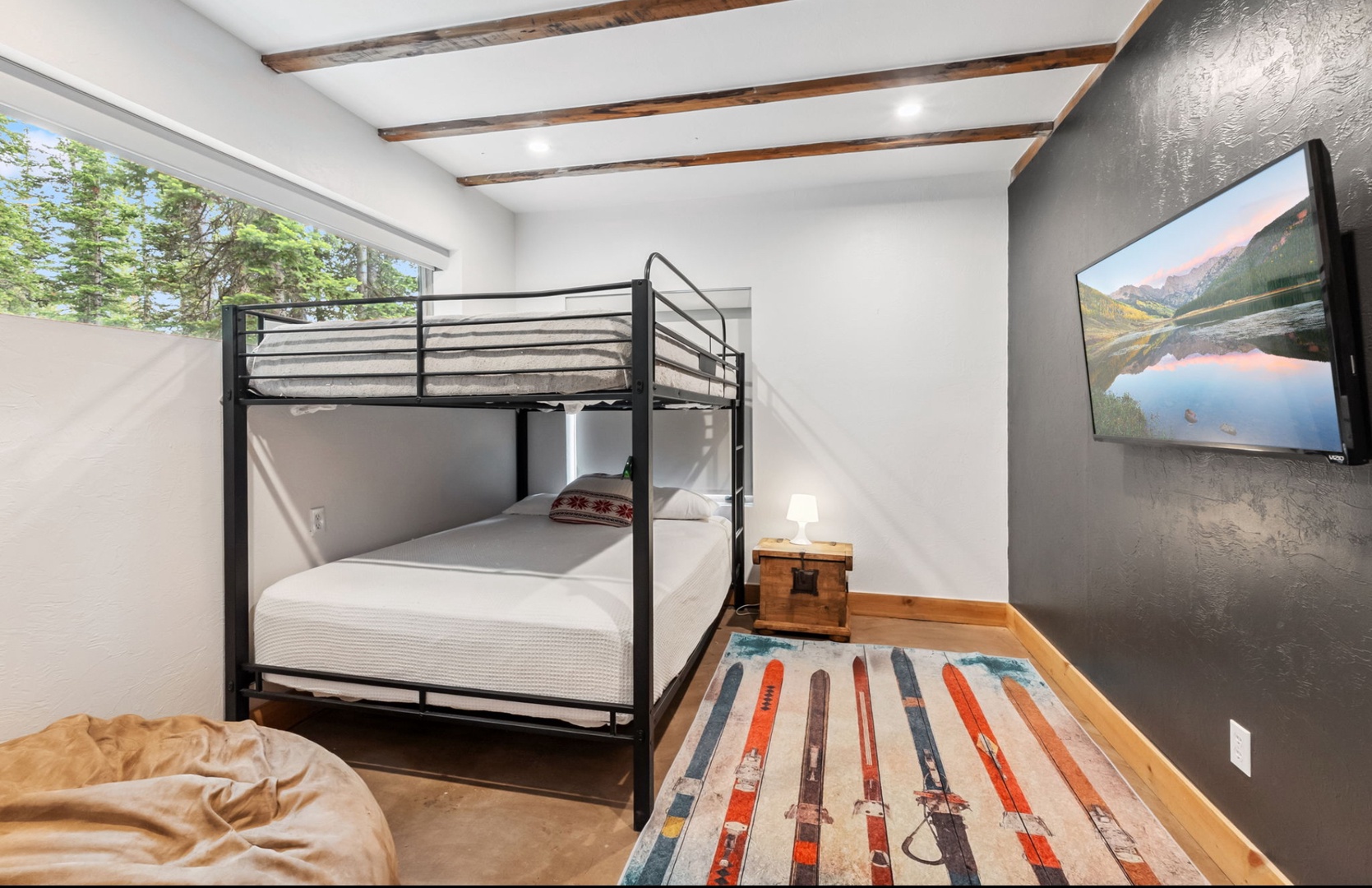 Your cozy mountain retreat features rustic wood beam ceilings, a bunk bed for extra guests, and natural light streaming through large windows. Unwind with mountain views on the flat-screen TV after a day exploring the slopes.