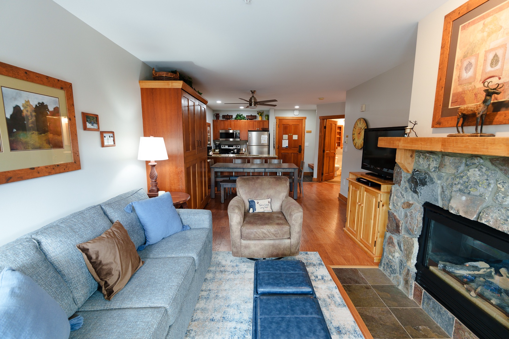 Relax in your spacious open-concept living area featuring a cozy stone fireplace, comfortable seating, and fully equipped kitchen - perfect for unwinding after your adventures.