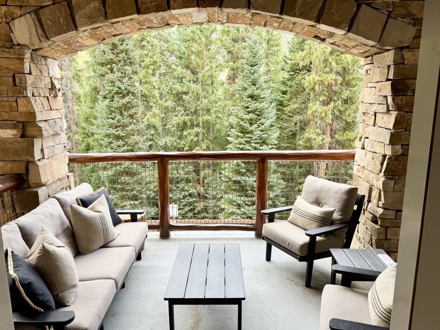 Sink into plush seating on your private balcony, framed by a stunning stone archway. The forest stretches out before you—a peaceful retreat where you can sip your morning coffee or unwind with a good book.