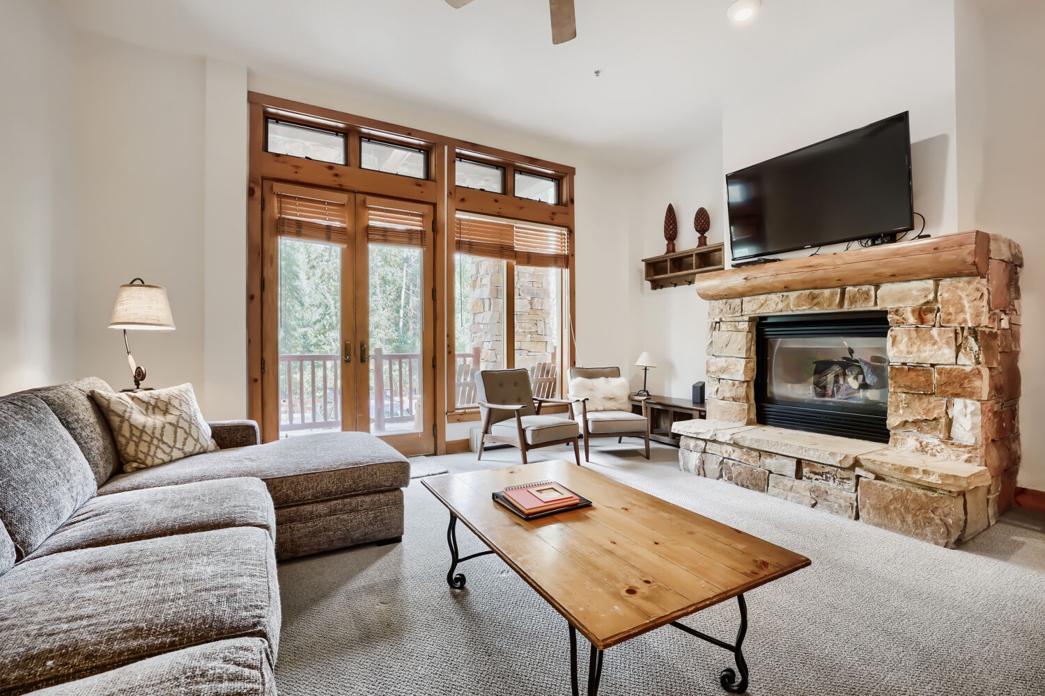 Curl up in this inviting living space where a cozy fireplace and mountain views await. Relax on the comfortable sofa, enjoy your favorite shows, and soak in the natural light streaming through the beautiful wooden doors.