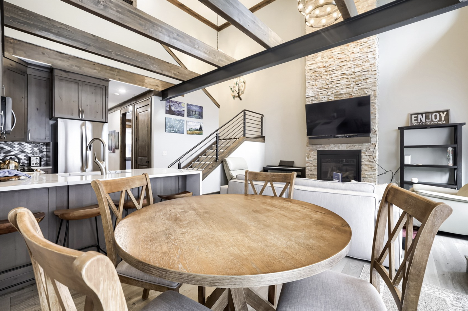 Step into your stunning open-concept retreat, where soaring vaulted ceilings with exposed beams, a striking stone fireplace, and modern elegance blend seamlessly. Gather around the spacious dining table or relax in your inviting living area.