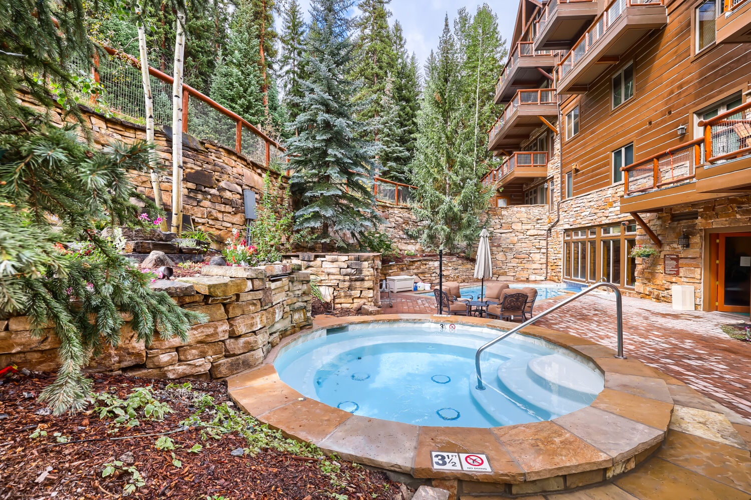 A hot tub nestled amid natural stone terraces and towering pines, inviting you to soak under the open sky after a day of mountain adventure.