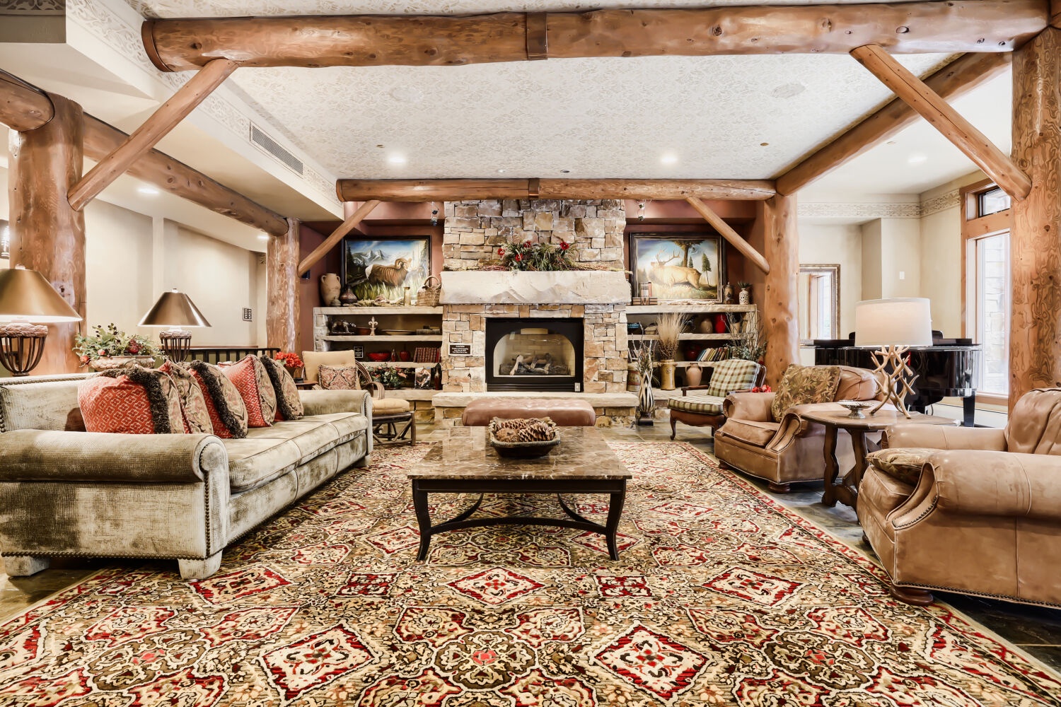 Sink into plush leather armchairs by your own stone fireplace, framed by rustic timber beams that soar overhead. This welcoming living room pairs mountain-lodge charm with refined comfort, inviting you to relax in style.