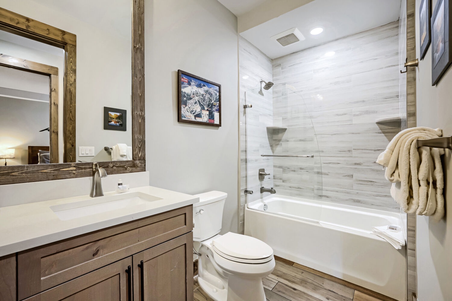 Freshen up in your modern bathroom, featuring a sleek tub-shower combo with wood-look tile and plush towels waiting for you.