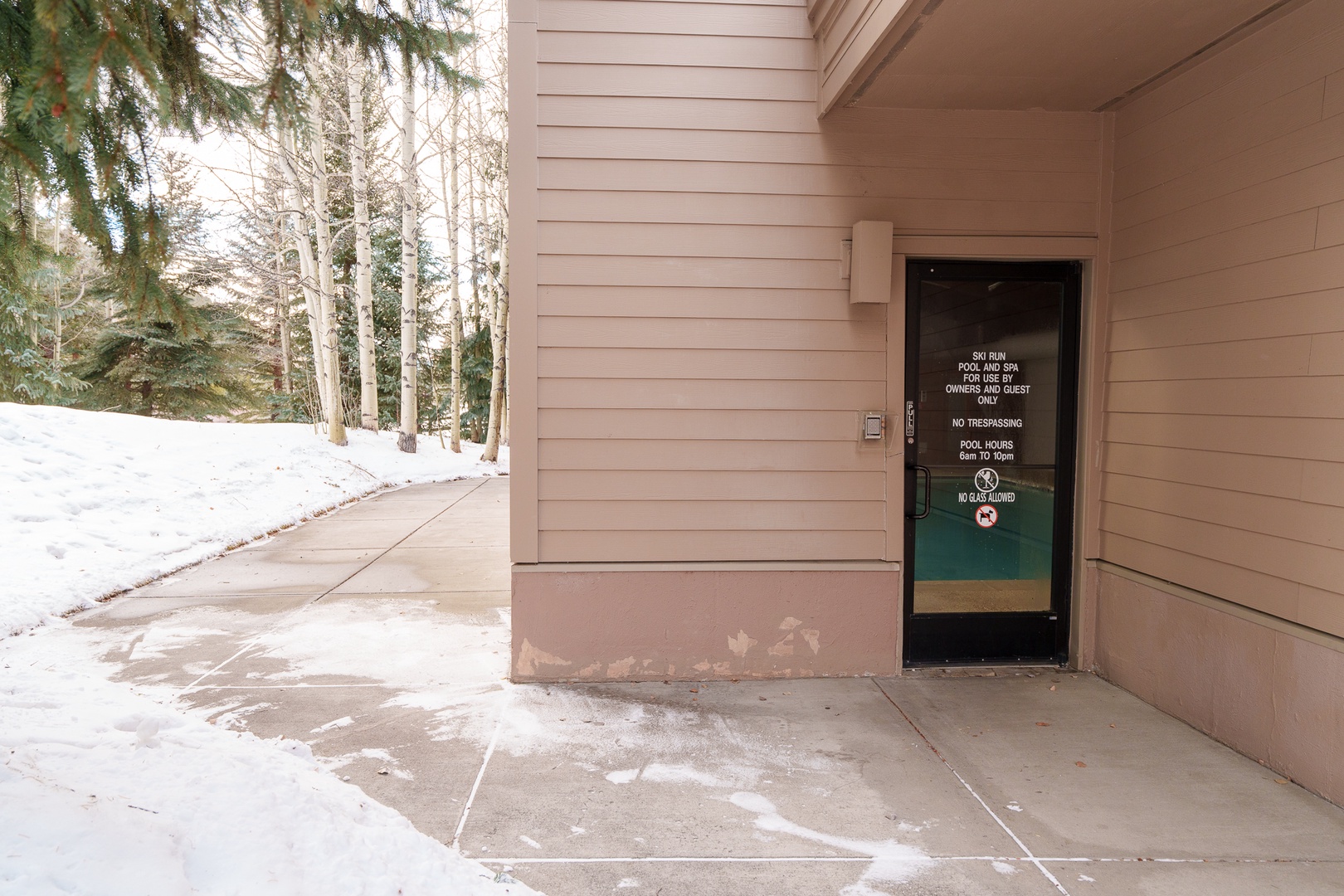 Property entrance featuring winter forest surroundings and covered entryway for easy arrival during snowy conditions.