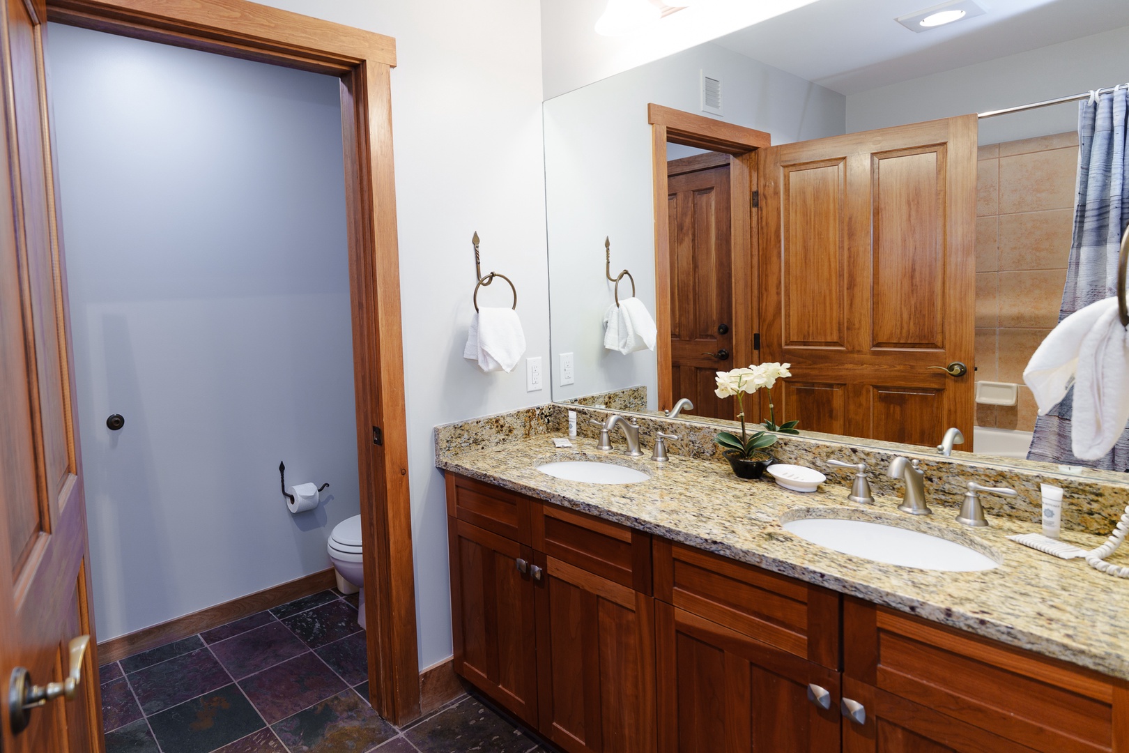 Your elegant bathroom features a granite double vanity with warm wood cabinetry, providing plenty of space for your morning routine in sophisticated comfort.