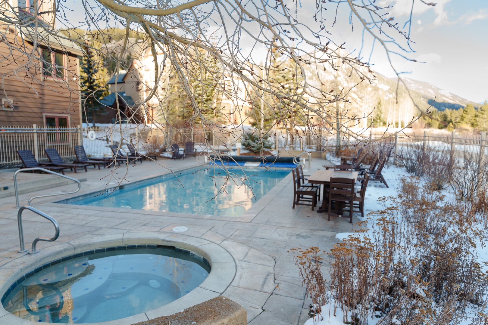 Winter scenery surrounds the property's outdoor pool and hot tub area, with snow-covered grounds and mountain views in the distance.
