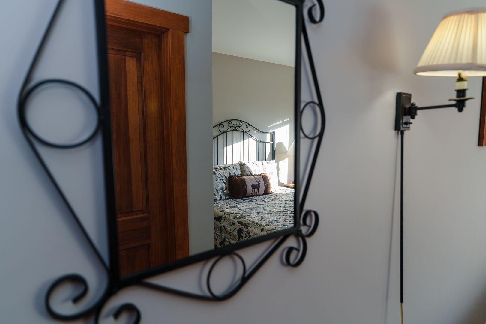 Your cozy bedroom reflected in an elegant wrought iron mirror, creating a warm and inviting atmosphere for your stay.
