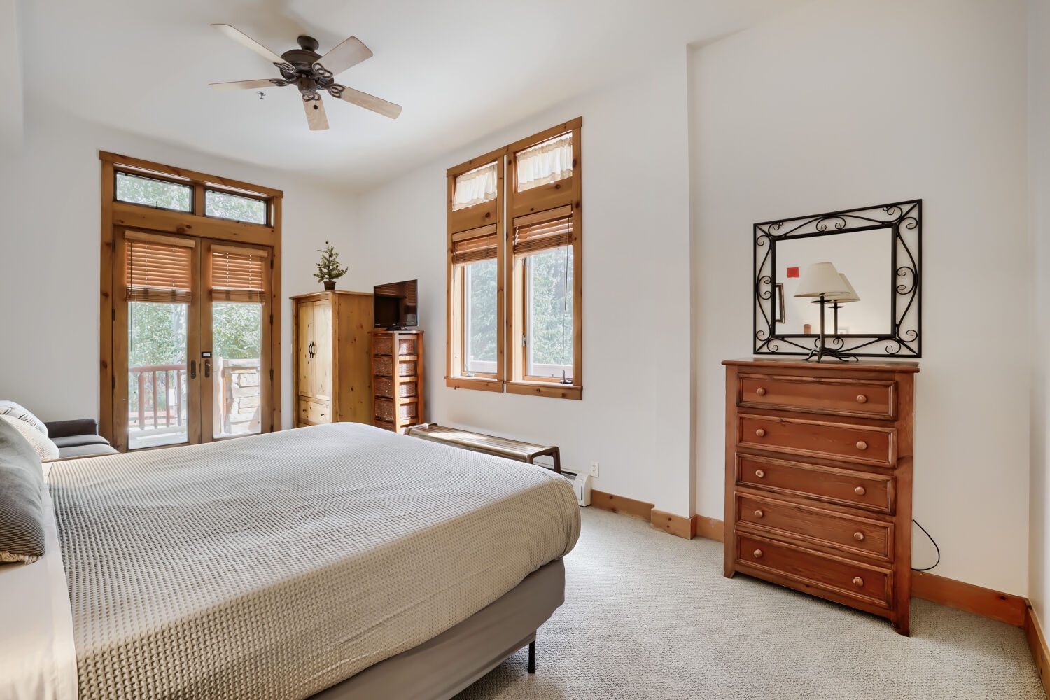 Your serene primary bedroom features warm wood tones and a private balcony entrance where you can step out to enjoy fresh mountain air and peaceful views through the transom windows.