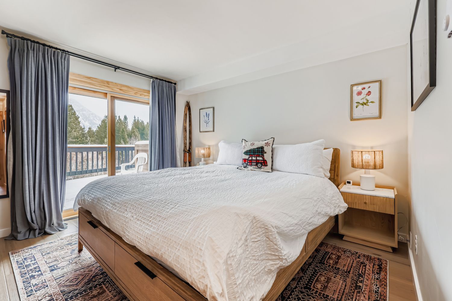 Drift off to sleep in this serene bedroom with crisp white linens, warm wood furnishings, and gentle natural light filtering through your private balcony doors.
